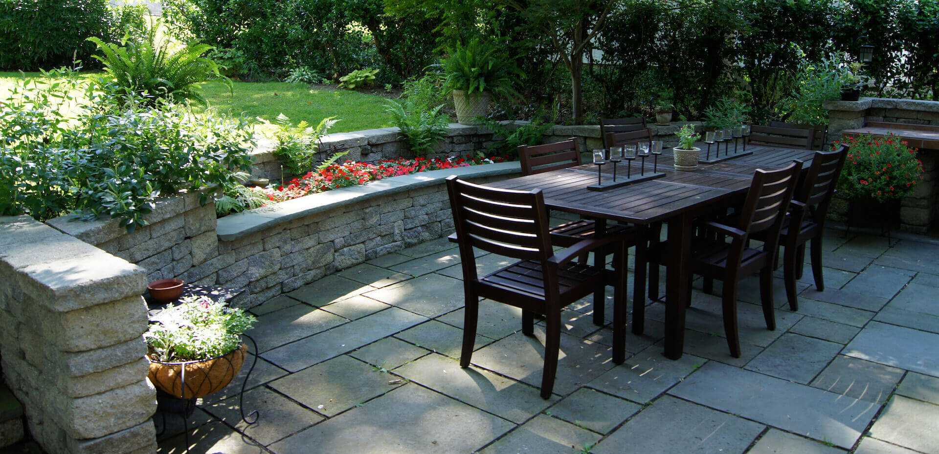 outdoor dark wood table surrounded by stone landscape architecture